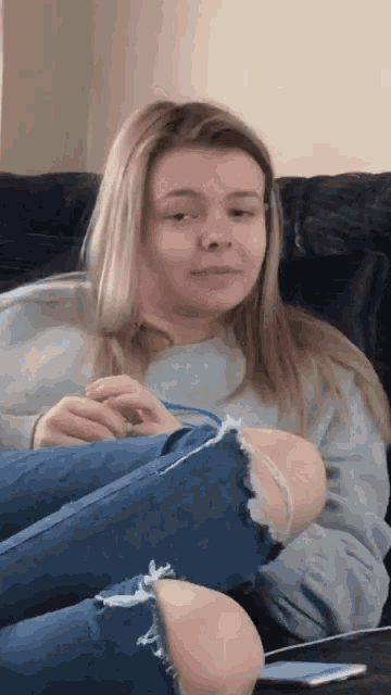 a young woman is sitting on a couch with her legs crossed