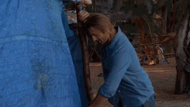 a woman in a black thong is standing in front of a blue tarp