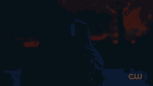a cw logo can be seen in the dark behind a couple
