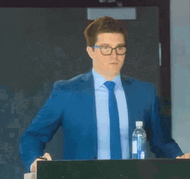 a man in a suit and tie stands at a podium