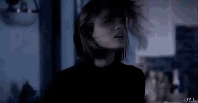 a close up of a woman 's face in a dark room with her hair blowing in the wind .