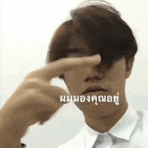 a man in a white shirt is covering his eyes with his finger .
