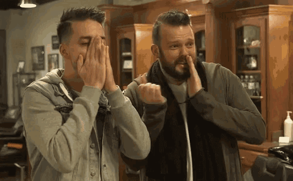 two men in a barber shop covering their faces with their hands