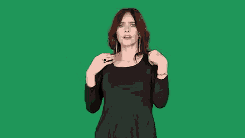 a woman in a black dress is making a funny face on a green screen .