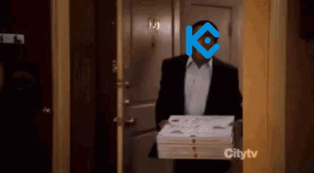 a man in a suit is carrying a stack of pizza boxes with a k on his face