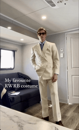 a man in a suit is standing in a room with the words my favourite rwrb costume