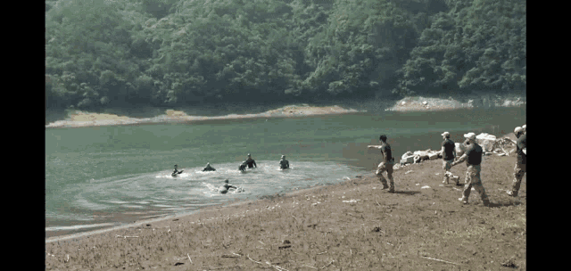 a group of people standing on a beach near a body of water