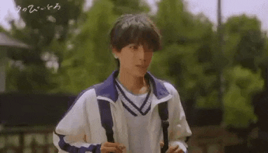 a young man wearing a white shirt and a blue jacket is carrying a backpack .