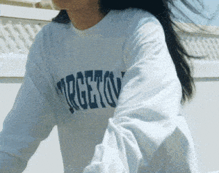 a woman wearing a white targeto shirt is standing in front of a white wall