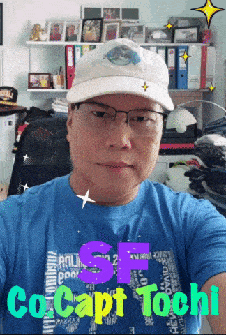 a man wearing glasses and a hat has the name co capt tochi on his shirt