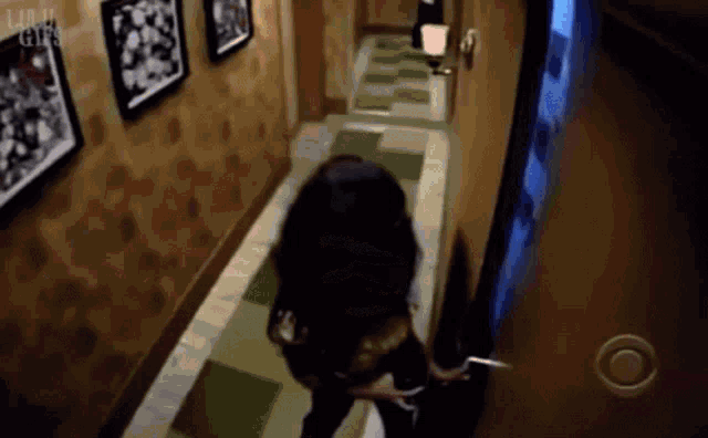 a woman is walking down a hallway with pictures on the wall