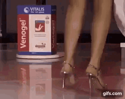 a woman wearing high heels is standing in front of a box that says venogel .