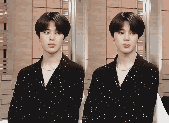 a man in a black shirt with white polka dots looks at the camera