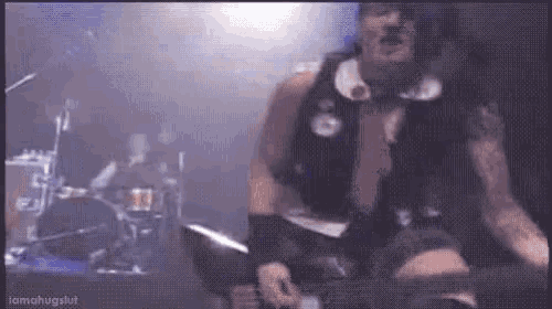 a man in a black vest is playing a guitar on stage .