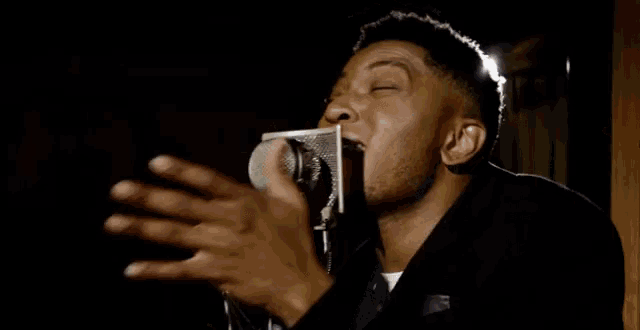 a man is singing into a microphone with a ring on his finger