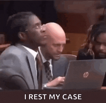 a man in a suit and tie is sitting at a table with a laptop computer .
