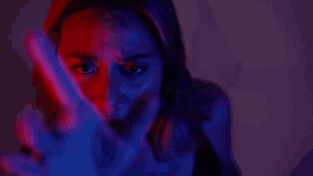 a woman is making a hand gesture with her hand in front of her face .