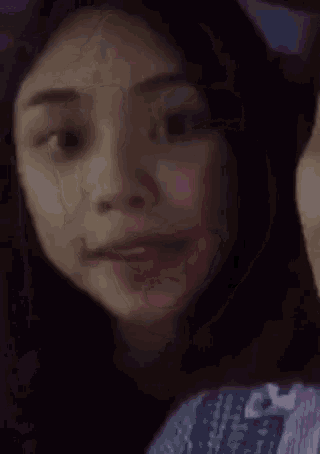 a close up of a woman 's face with purple light behind her .