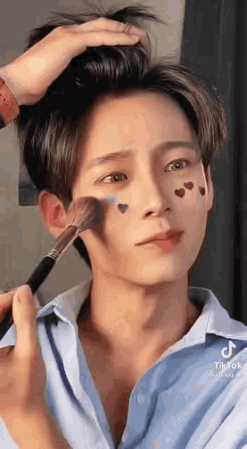 a person is applying makeup to a man 's face .