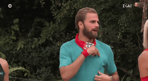 a man in a blue shirt with a red bandana around his neck has the number 12 on the screen behind him