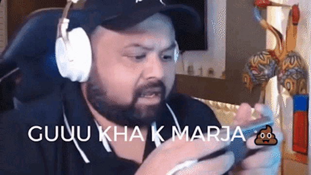 a man with a beard wearing headphones is playing a video game on his phone .