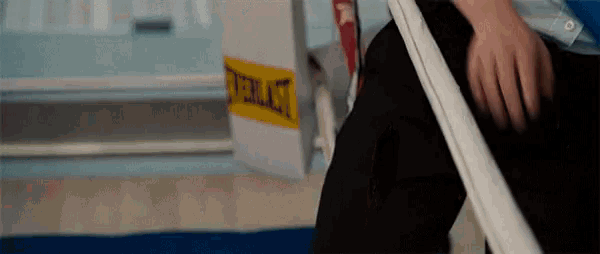 a person is sitting in a boxing ring next to a box that says everlast on it .