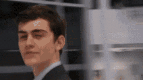 a man in a suit and tie is looking at the camera with his eyes closed