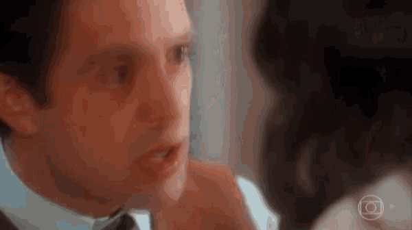 a man in a suit and tie is looking at a woman in a white shirt .