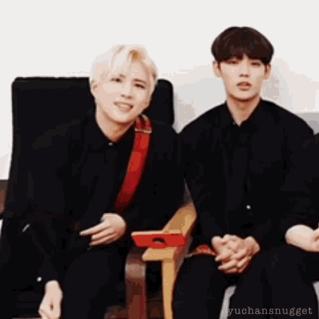 two young men are sitting next to each other in chairs and smiling .
