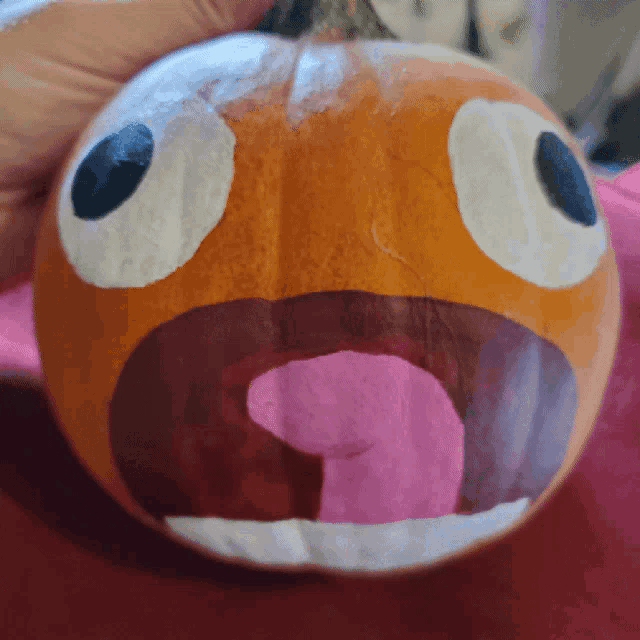 a person is holding a pumpkin with a face carved into it