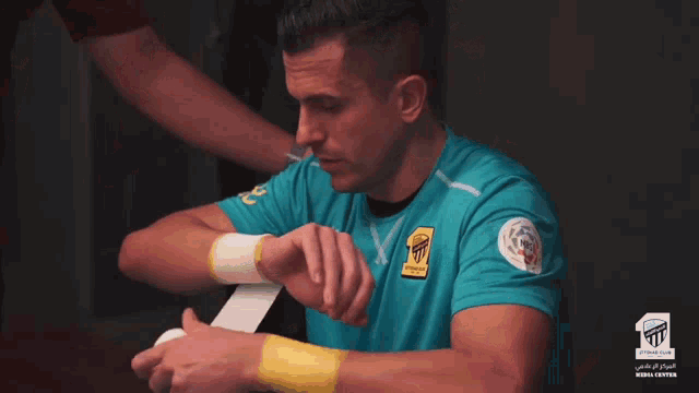 a man in a blue shirt with a yellow wristband has a sticker on his wrist that says ' a '