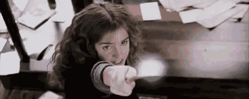 hermione granger is pointing at the camera with her wand .