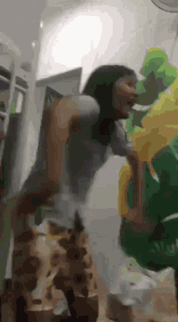 a woman is standing next to a green balloon and laughing .