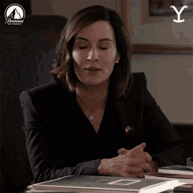 a woman is sitting at a desk with a paramount network logo behind her