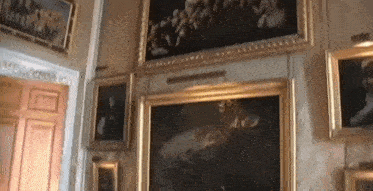 several paintings are hanging on a wall in a museum