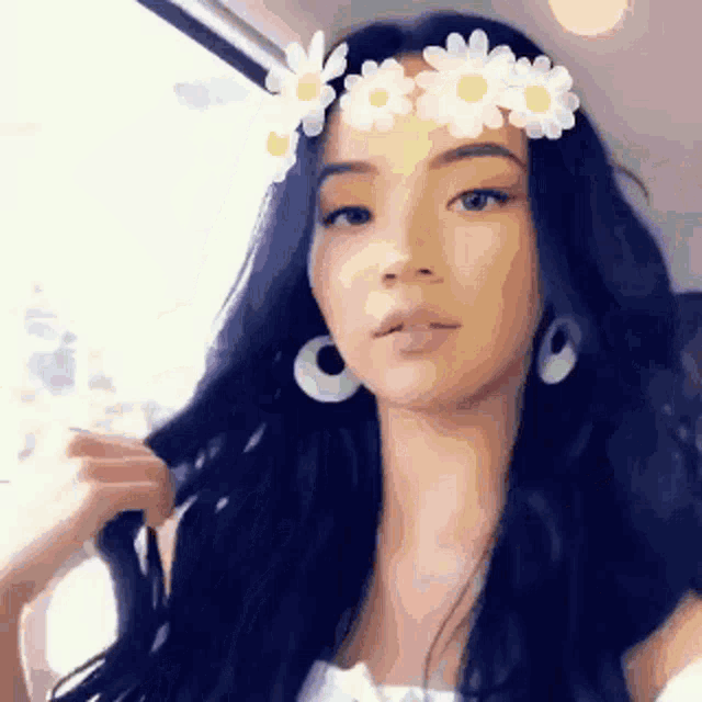 a woman wearing a flower crown on her head looks at the camera