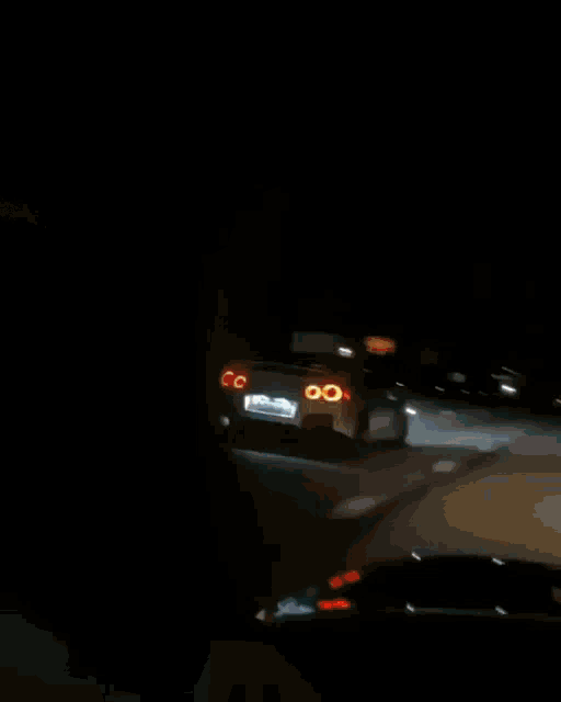a car is driving down a road at night and the tail light is on fire