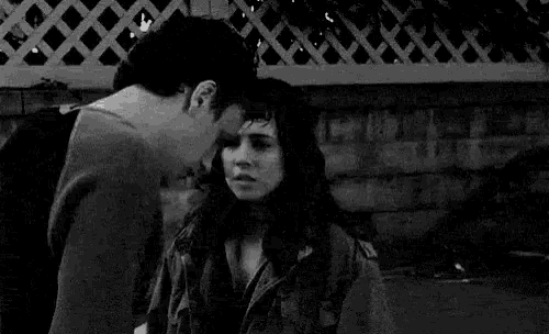 a black and white photo of a man and woman kissing .