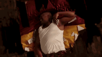 a man in a white tank top is laying on a bed with a bunch of money