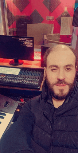 a man with a beard is standing in front of a computer monitor that says yamaha