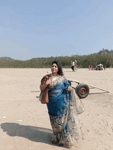 a woman in a blue saree stands on a beach with a red arrow pointing to the letter m.