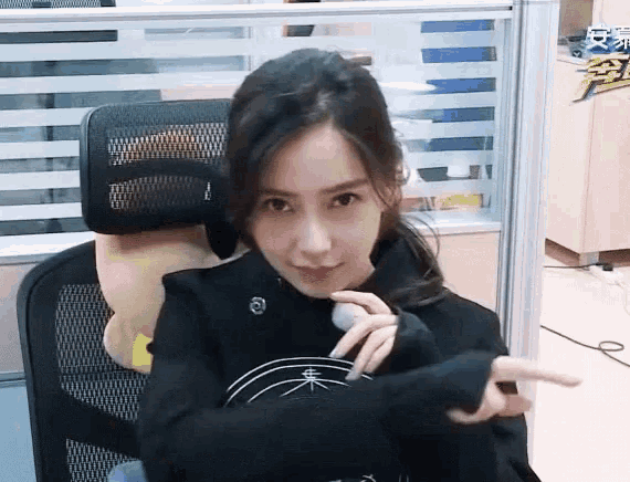 a woman is sitting in an office chair making a funny face .
