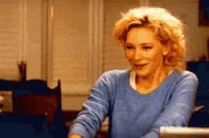 a woman wearing a blue sweater is smiling