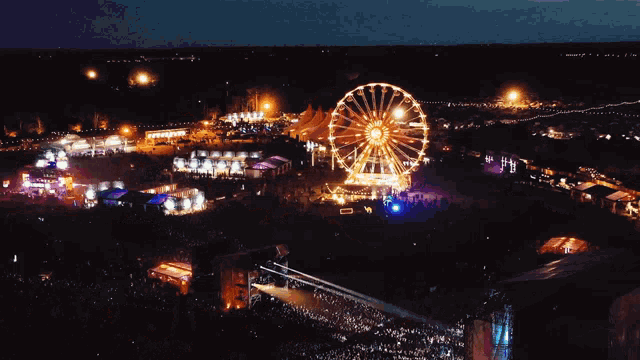 an aerial view of a music festival with a ferris wheel in the background