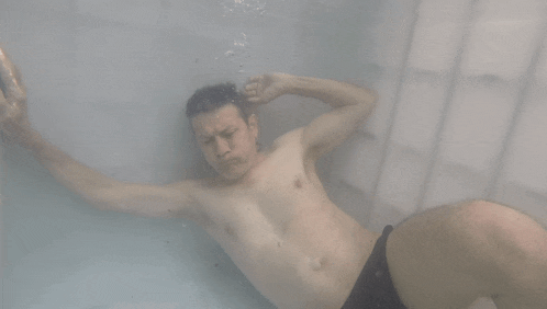 a shirtless man is laying in a bathtub
