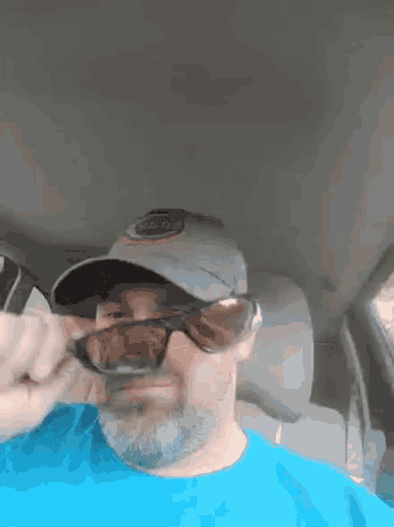 a man wearing sunglasses and a hat is sitting in the back seat of a car .