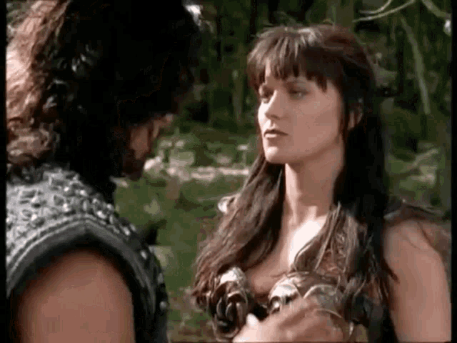 a man and a woman are looking at each other in a forest .