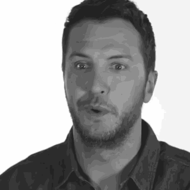 a black and white photo of a man with a beard and a denim shirt
