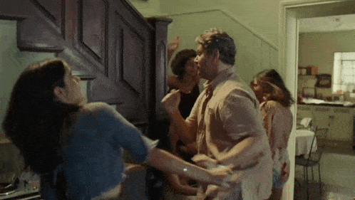 a group of people are dancing in a kitchen while a man kisses a woman
