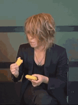 a man in a black suit is holding a piece of bread